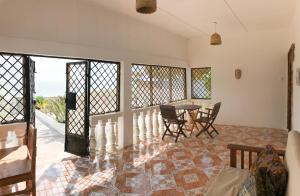a living room with a table and chairs and a balcony at House on the beach in Jambiani