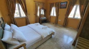 a bedroom with a large white bed with windows at Jibreen Hotel in Bahlāʼ