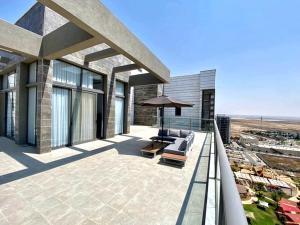 a balcony of a building with a couch and an umbrella at Penthouse à Manhattan Netivot in Netivot
