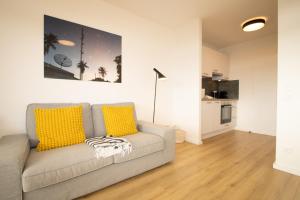 a living room with a gray couch with yellow pillows at Sylt for Friends in Hörnum