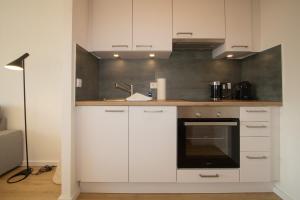 a kitchen with white cabinets and an oven at Sylt for Friends in Hörnum
