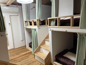 a room with four bunk beds in a room at ゲストハウスまちかど Guest House MACHIKADO in Ibusuki