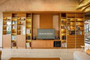 a living room with a tv and bookshelves at Bumi Anyom Resort by Nexura in Pikatan
