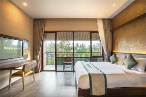 a bedroom with a bed and a desk and a television at Bumi Anyom Resort by Nexura in Pikatan