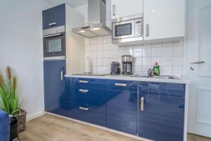 a kitchen with blue cabinets and a microwave at Lister Tor 11 in List +6 photos