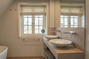a bathroom with two sinks and a tub and two windows at Lachmöwe in List +22 photos