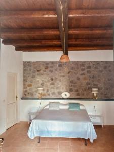 a bedroom with a bed and a stone wall at Dépendance Liscio in Filicudi