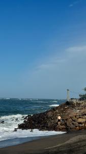 a rocky beach with a building on the ocean at Seseh Studio in Cemagi
