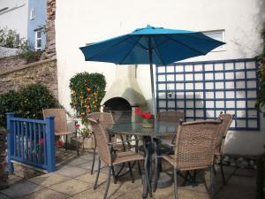 a table and chairs with an umbrella on a patio at Upper Cottage, Brixham in Brixham