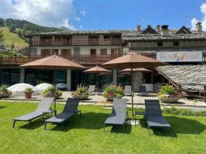 a group of chairs and umbrellas in front of a building at Hotel Chalet du Soleil in Torgnon