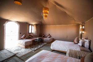 a room with two beds and a table in a tent at Casa house in Merzouga