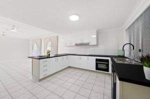 a kitchen with white cabinets and a black counter top at Darra guest house in Brisbane
