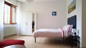 a white bedroom with a bed and a red couch at Maya Suite & Garden in Sarteano
