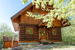 a log cabin in the woods with a tree at Belvedere sur le Lac Lodge in Sainte-Adèle