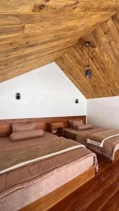 two beds in a room with wooden ceilings at Asokabin House in Diyeng
