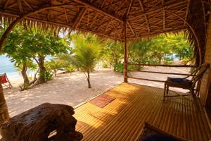 a porch of a hut with a chair on the beach at Dos Playa EcoCamp Daracoton Island in El Nido +37 photos