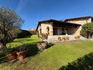 a house with potted plants in front of a yard at Luxury Villa Esmeralda in Suances