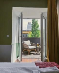 a bedroom with a balcony with a chair and a window at North-Hotel in Hamburg