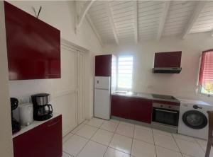 eine Küche mit roten Schränken und einem weißen Kühlschrank in der Unterkunft Paradis des sables B in La Désirade