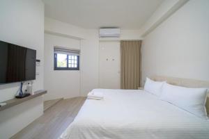 a white bedroom with a large bed and a flat screen tv at Yunheyue B&B in Suao +4 photos