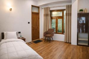 a bedroom with a bed and a chair and a window at RH Guest House Leh in Leh