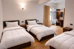 a hotel room with two beds and a desk at RH Guest House Leh in Leh