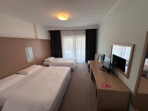 a hotel room with two beds and a flat screen tv at Hotel Driloni in Pogradec