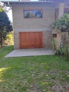 a brick house with a wooden garage door at Loft 73 in Bento Gonçalves +2 photos