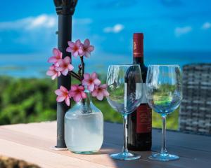 a table with two wine glasses and a bottle of wine at Mountain Chalet with Awesome Sea View in Loma Partida