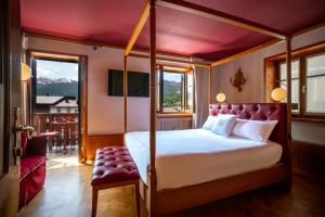a bedroom with a canopy bed and a balcony at Ambra Cortina Luxury&Fashion Hotel in Cortina dʼAmpezzo