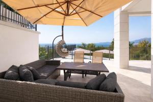 a patio with a couch and a table and an umbrella at Sea View Residence with Pool & Private Terrace in Krstac