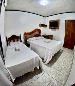 a hotel room with two beds and a tv at Hotel e Pousada França in Manhã