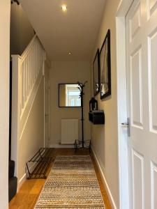 a hallway with a white door and a rug at 2 Brocklehurst Cottages in Buxton