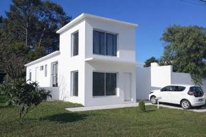 a white car parked in front of a white house at Refugio del bosque - Casa con jacuzzi descanso en Piriapolis in Piriápolis +6 photos