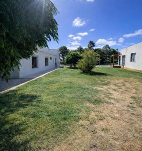 a grassy yard next to a white building at Refugio del bosque - Casa con jacuzzi descanso en Piriapolis in Piriápolis