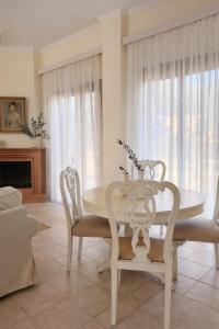 a white dining room with a table and chairs at Melitta Villa in Ágios Ioánnis