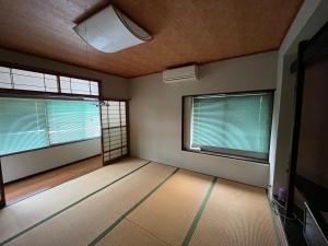 an empty room with two windows and a television at 民泊 シェアハウス北浦 in Senboku