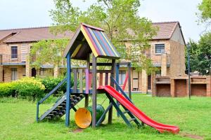 a playground with a slide in a yard at Cozy Comfortable Apartment with pool in Pretoria