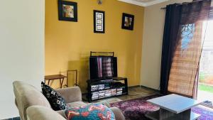 a living room with a couch and a tv at Blasto & Esita Cottages in Bunamwaya