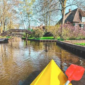 a yellow kayak in a river with a bridge at Tinyhouse Giethoorn in Giethoorn