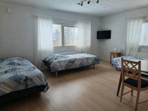 a bedroom with two beds and a flat screen tv at Nivan Majoitus Nivan koulu in Joensuu