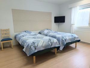 a bedroom with two beds and a tv on the wall at Nivan Majoitus Nivan koulu in Joensuu +1 photo