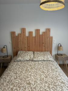 a bedroom with a large bed with a wooden headboard at Cottage des Lacs in Puttelange-aux-Lacs