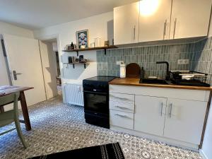 a kitchen with white cabinets and a sink and a table at Stadtwohnung Hygge Home in Neustadt in Holstein