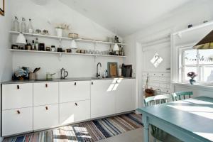 a kitchen with white cabinets and a table at Charming Tiny House In Sønderho in Fanø