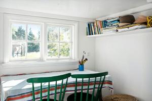 a room with a table with two green chairs and a window at Charming Tiny House In Sønderho in Fanø