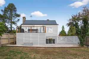 a small white house in a yard with a fence at Cedar Cottage Daylesford in Daylesford