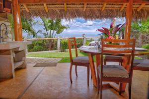 a dining room with a table and chairs and the ocean at VILLA PANORAMA NOSY BE in Nosy Be