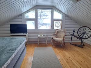 a bedroom with a bed and a chair and windows at Villa Kalkonniemi in Kemijärvi