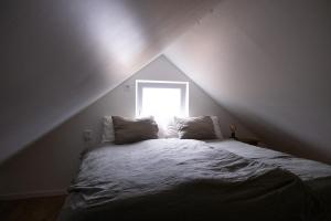 a bed with two pillows in a attic with a window at Bokskogen stugby hus två in Jönköping